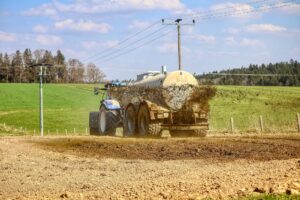 Landwirt fährt mit Traktor und Güllefass über das Feld